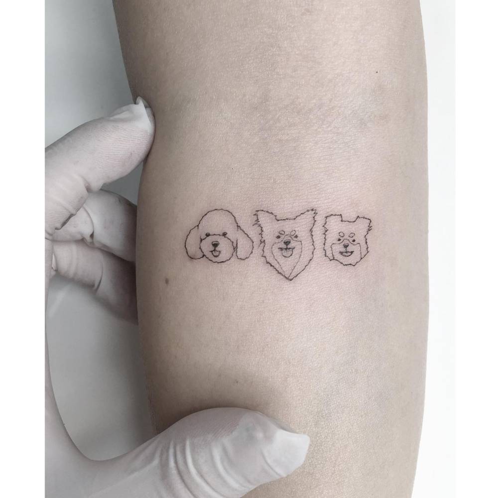 Fine line style minimalist dogs portrait tattooed on the inner forearm.
