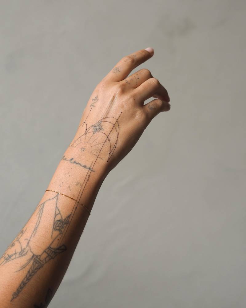 Fine line style ornamental design tattooed on the hand and wrist.