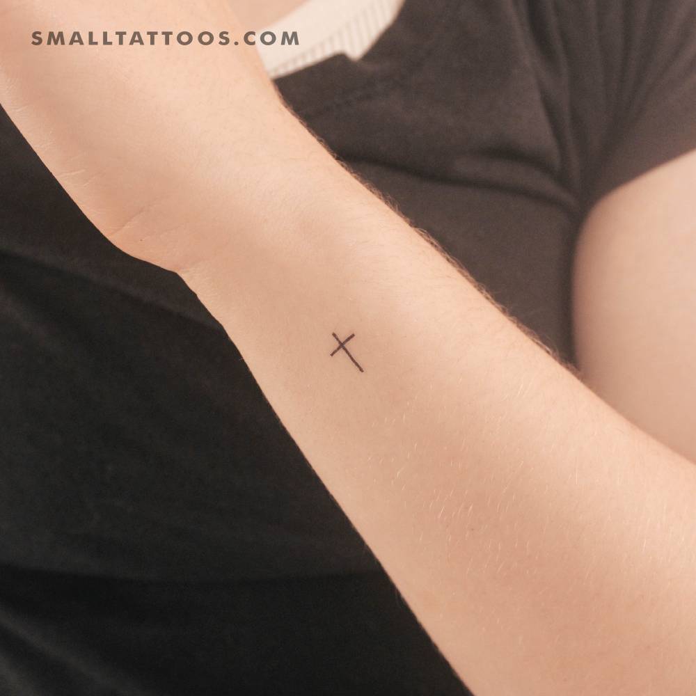 Small minimalist cross temporary tattoo located on the wrist.