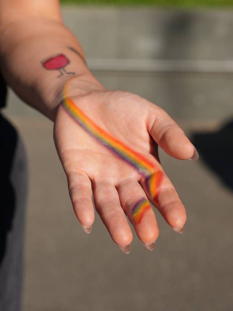 Rainbow tattoo in watercolor style located on the palm.
