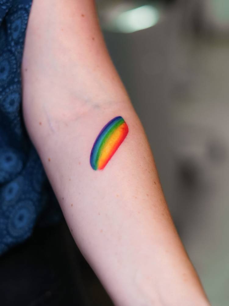 Visible spectrum brush stroke tattoo done on the inner forearm.