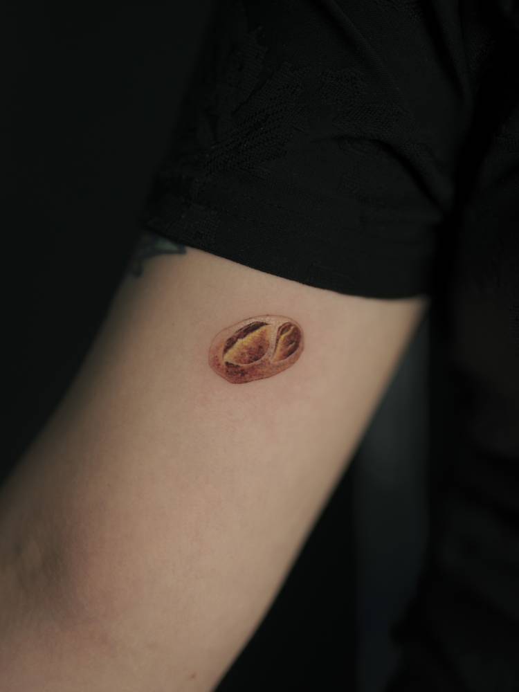 Micro-realistic style bread tattoo done on the inner arm.
