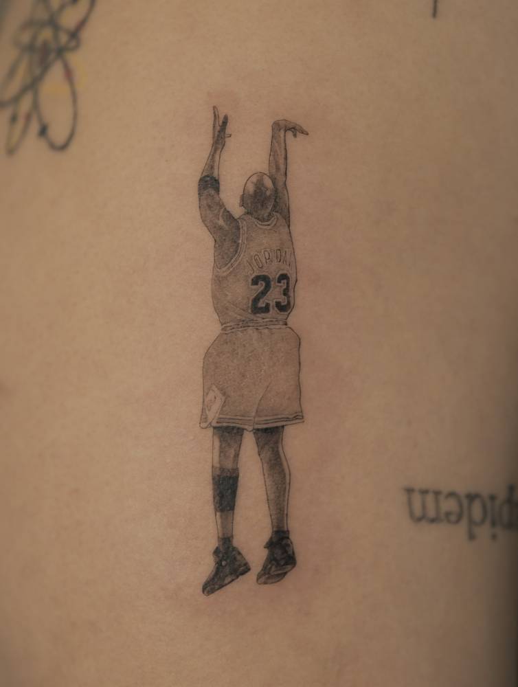 Michael Jordan tattoo in illustrative style located on the upper arm.