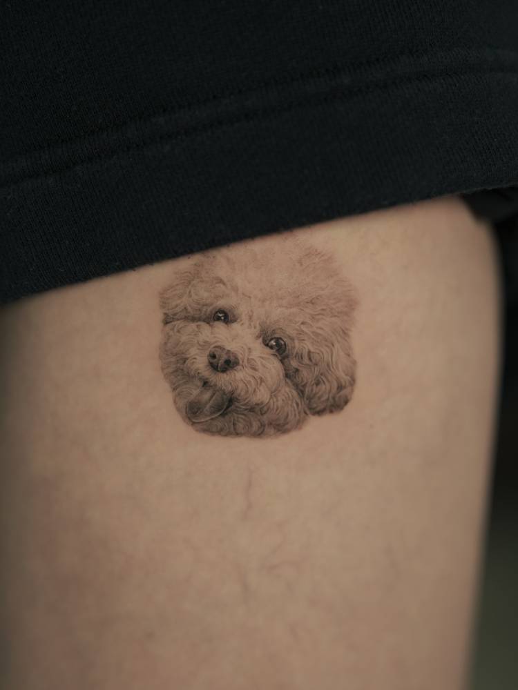 Cute Poodle portrait tattoo in micro-realism located on the thigh.