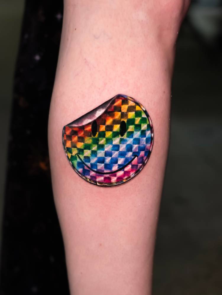 Smiley holographic sticker tattooed on the calf.