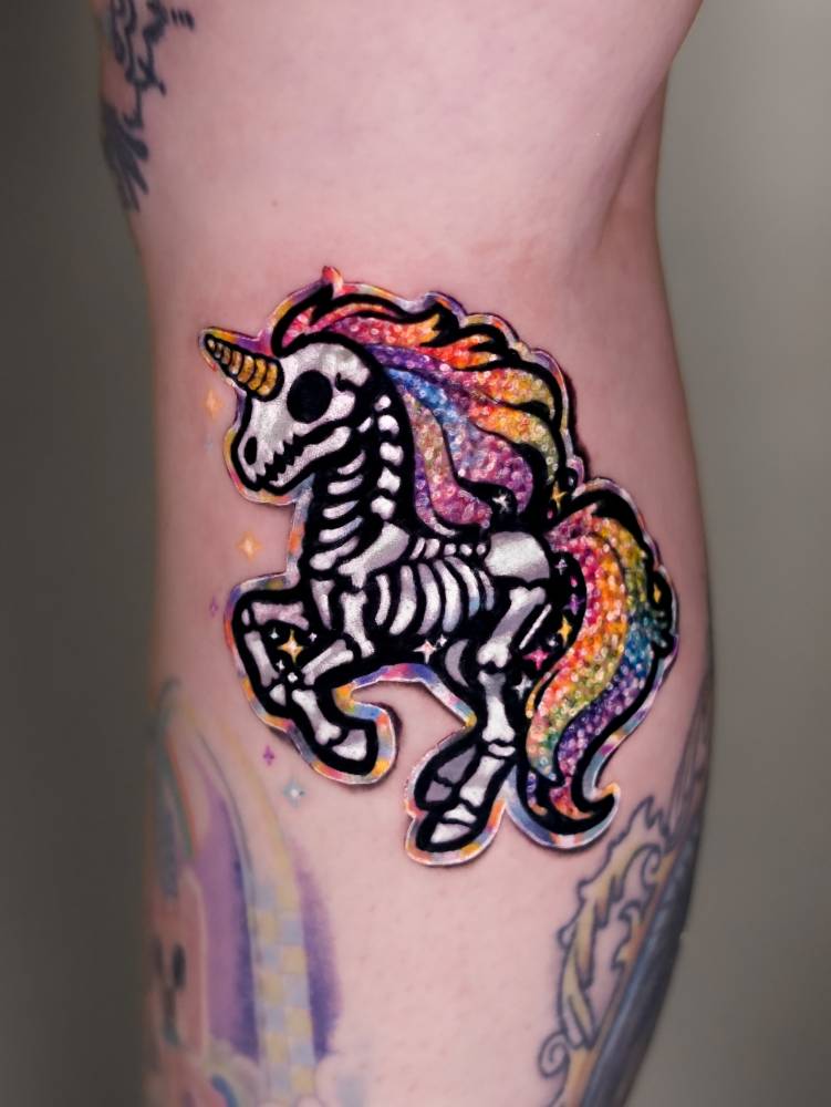 Skeleton unicorn sticker tattoo located on the calf.