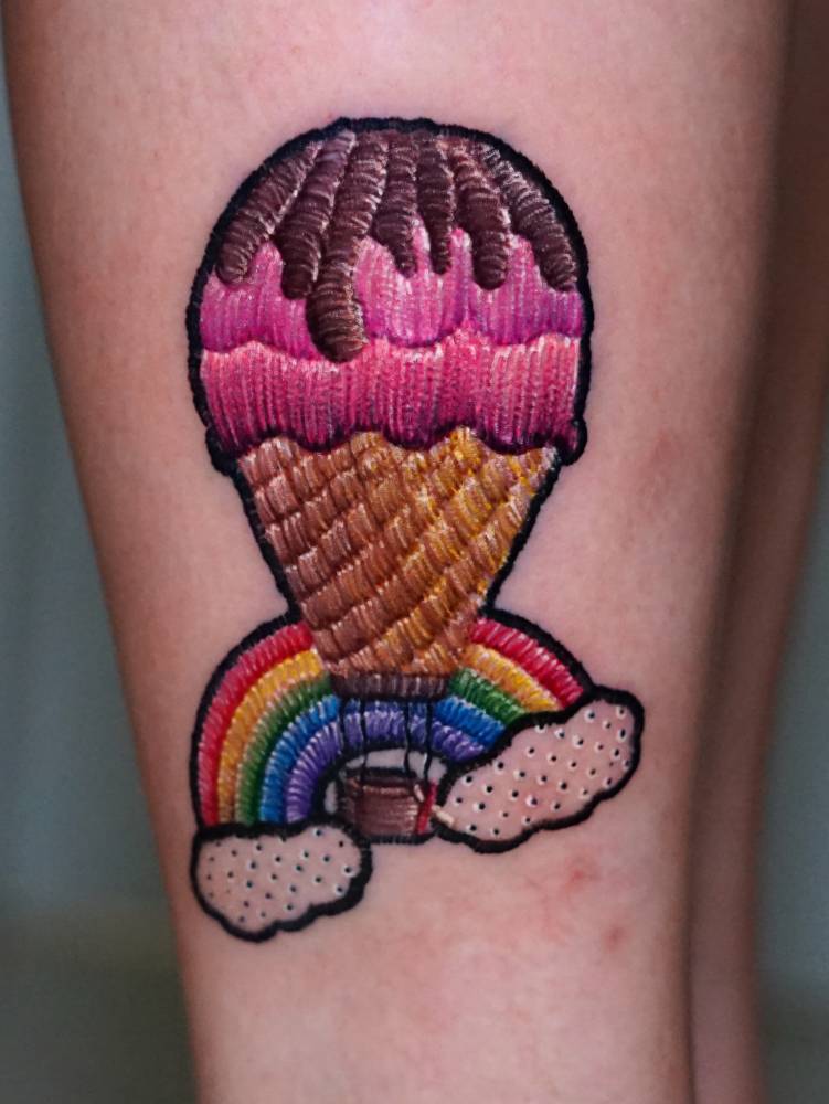 Ice cream cone hot air balloon tattoo located on the thigh, embroidery style.