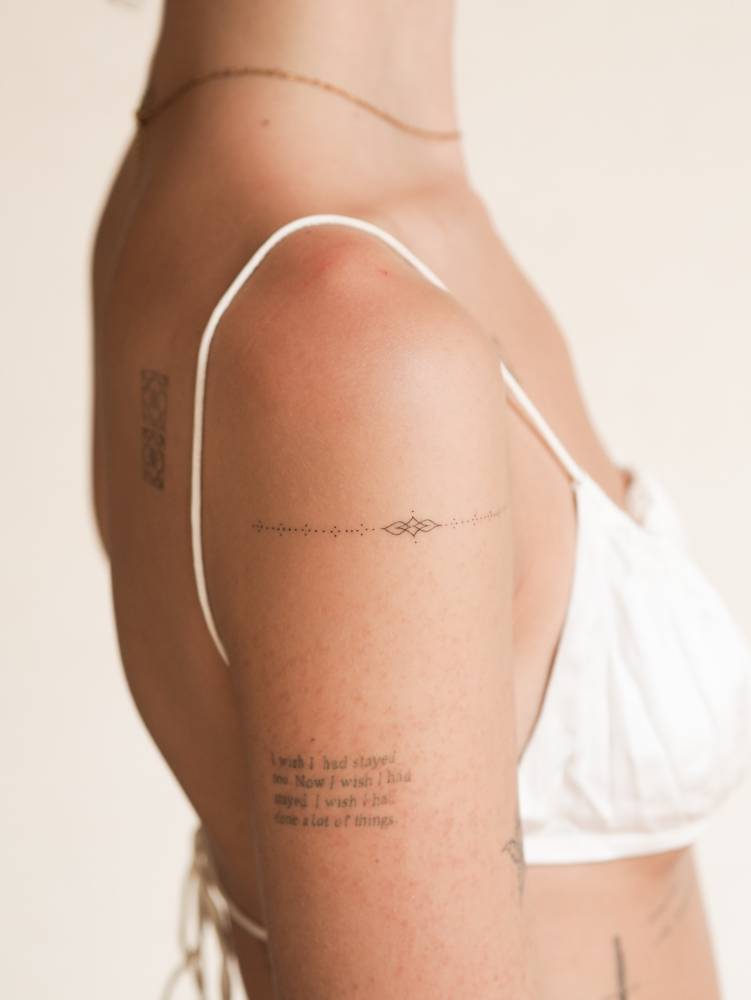 Fine line style ornamental tattoo located on the upper arm.