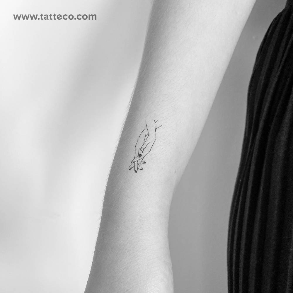 Holding hands temporary tattoo located on the wrist.