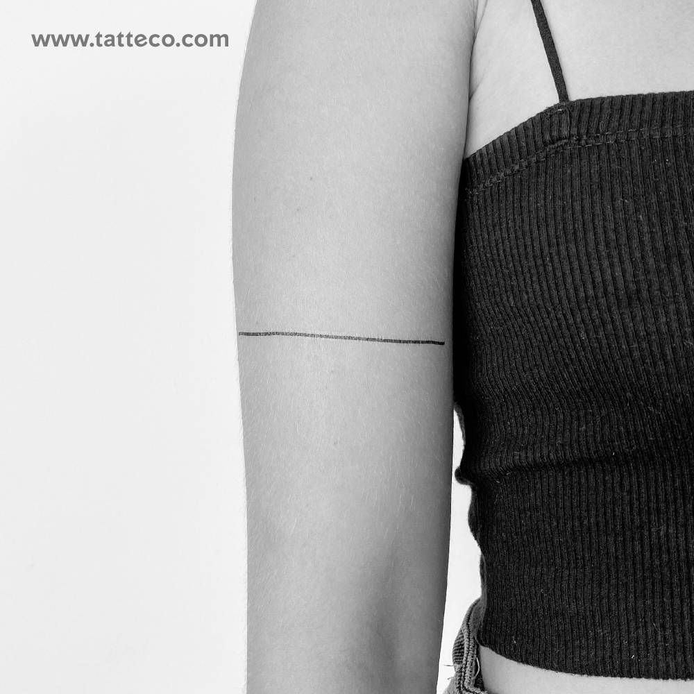 Straight line temporary tattoo located on the upper arm.
