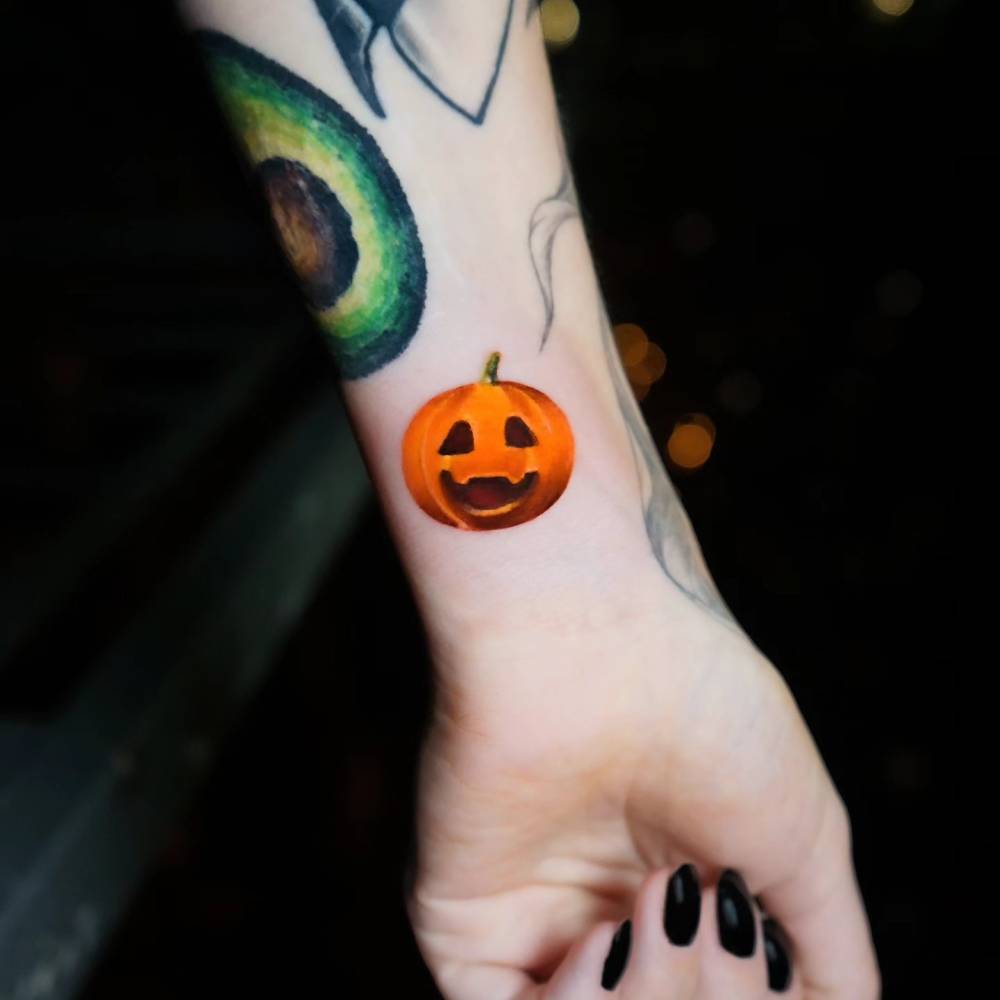 Jack-o-lantern tattoo located on the wrist, micro-realistic style.