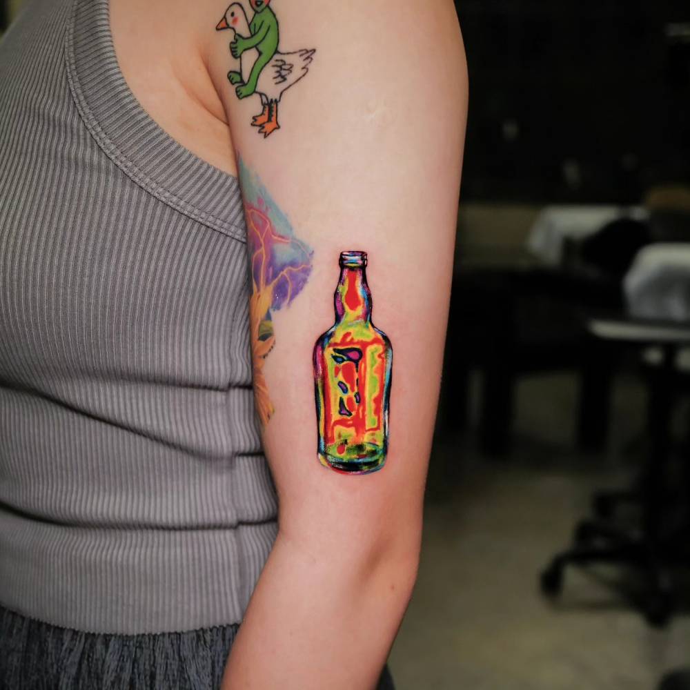 Pop art style bottle tattoo located on the upper arm.