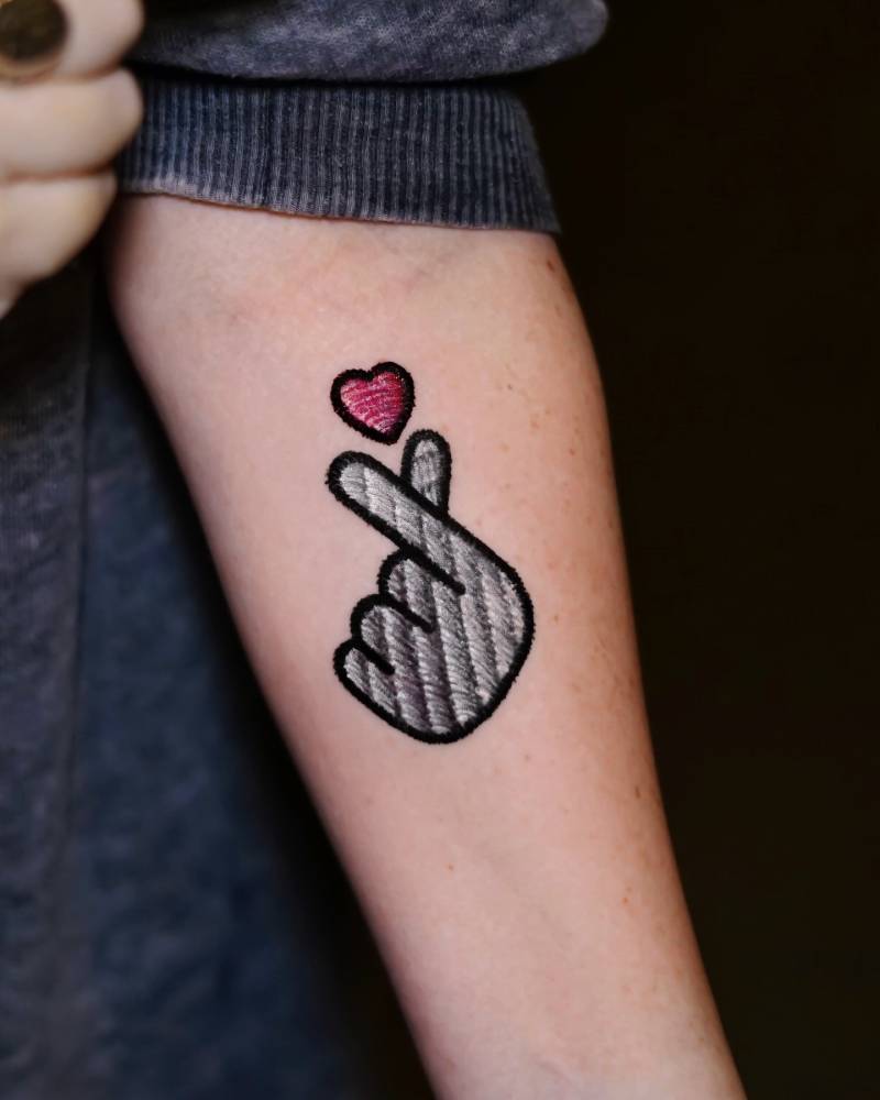 Korean finger heart patch tattoo located on the inner forearm.
