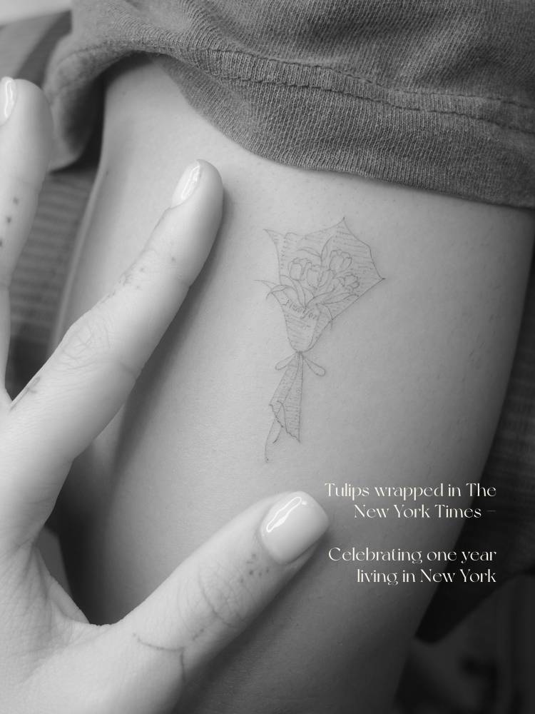 Tulips flower bouquet tattoo in fine line style located on the upper arm.