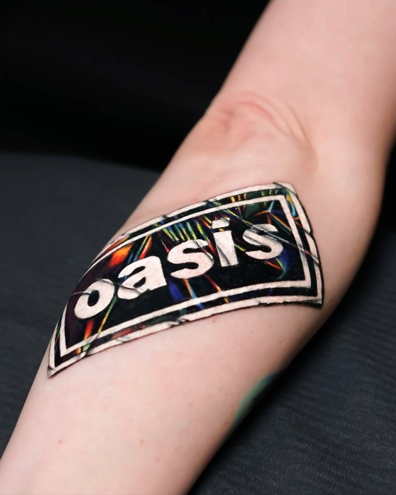 Oasis sticker tattoo located on the forearm.