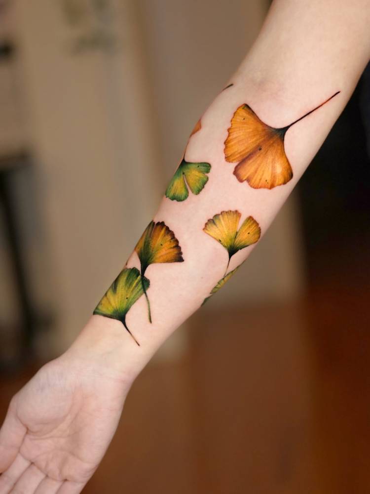 Ginkgo leaves tattoo in watercolor style located on the inner forearm.
