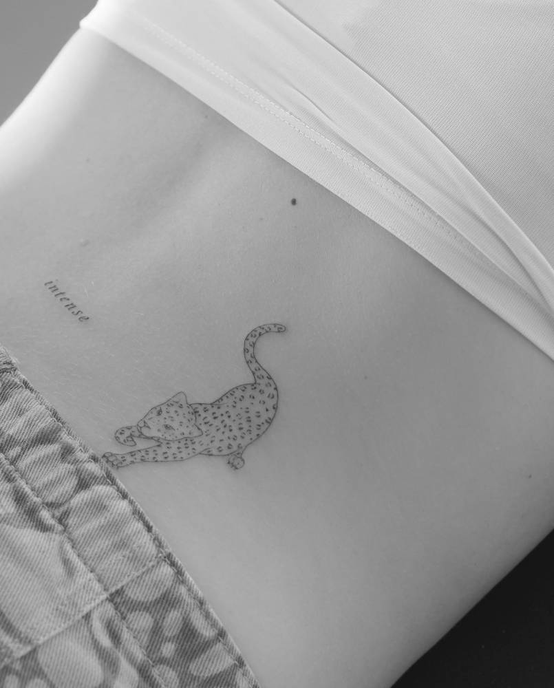 Word "intense" and leopard tattoos located on the lower back.