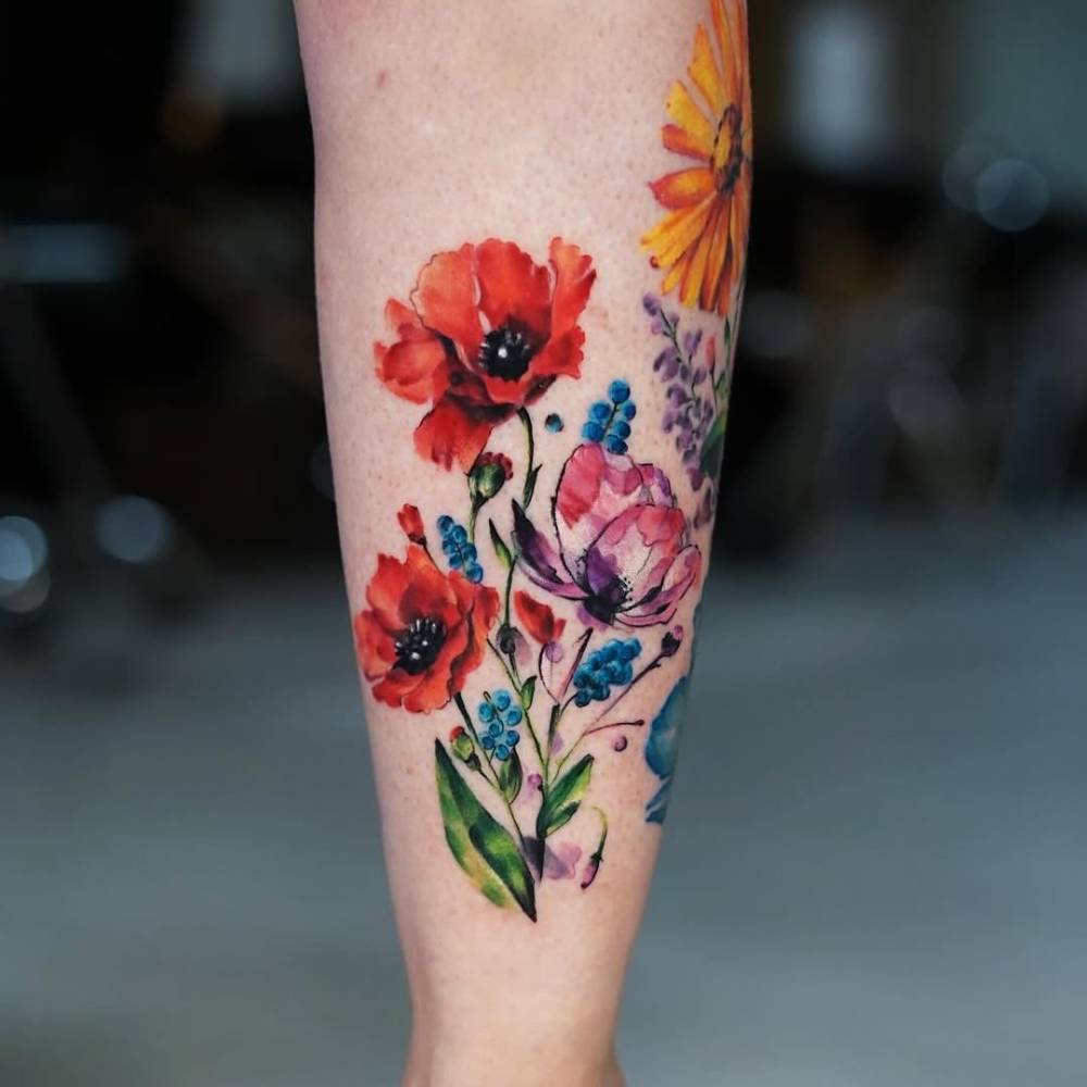 Watercolor style poppy flowers tattoo located on the shin.