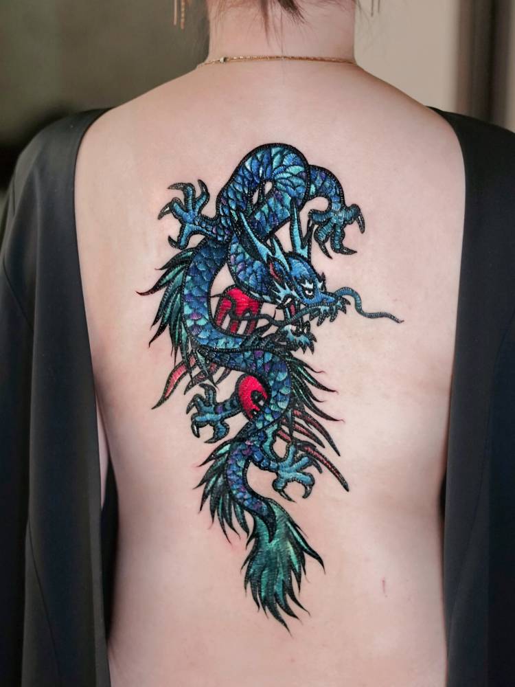 Embroidery style dragon tattoo located on the back.