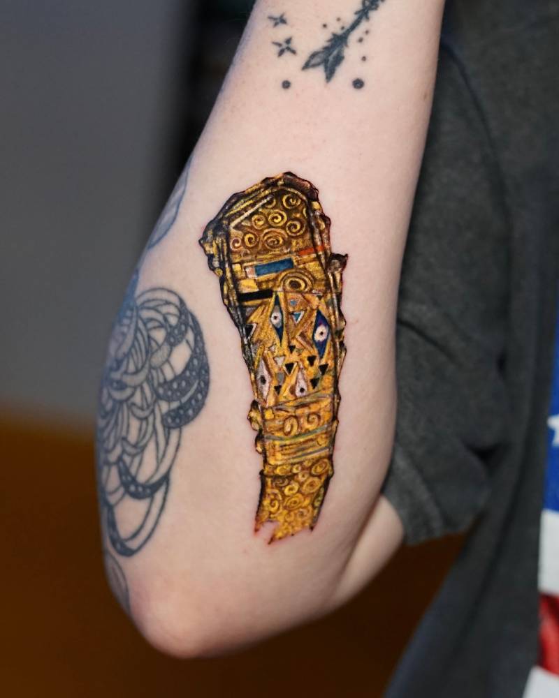 Klimt golden brushstroke tattoo located on the inner forearm.