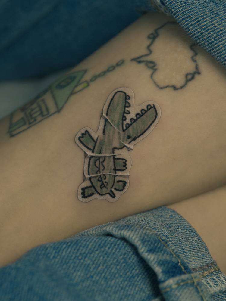 Crocodile doodle sticker tattoo located on the ankle.