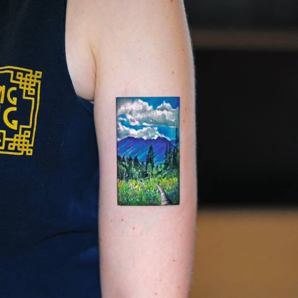 Micro-realistic style mountain landscape tattoo located on the upper arm.
