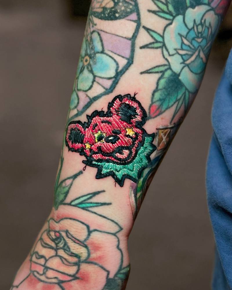 Bear head patch tattoo in embroidery style done on the wrist.