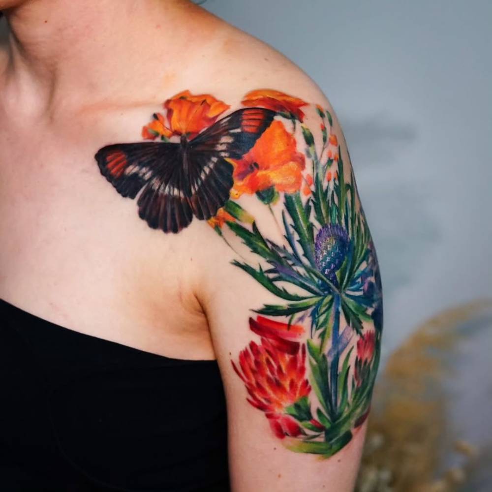 Watercolor style floral design tattoo located on the shoulder.