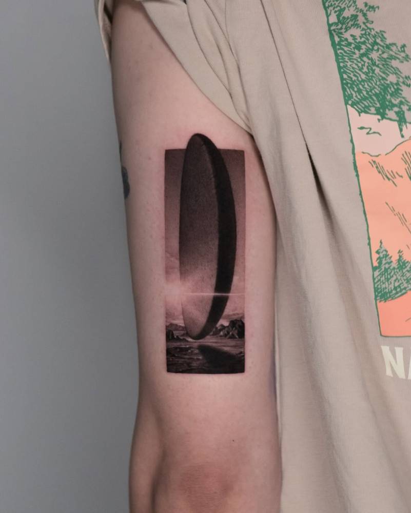 Arrival (2016) tattoo located on the tricep, micro-realistic style.