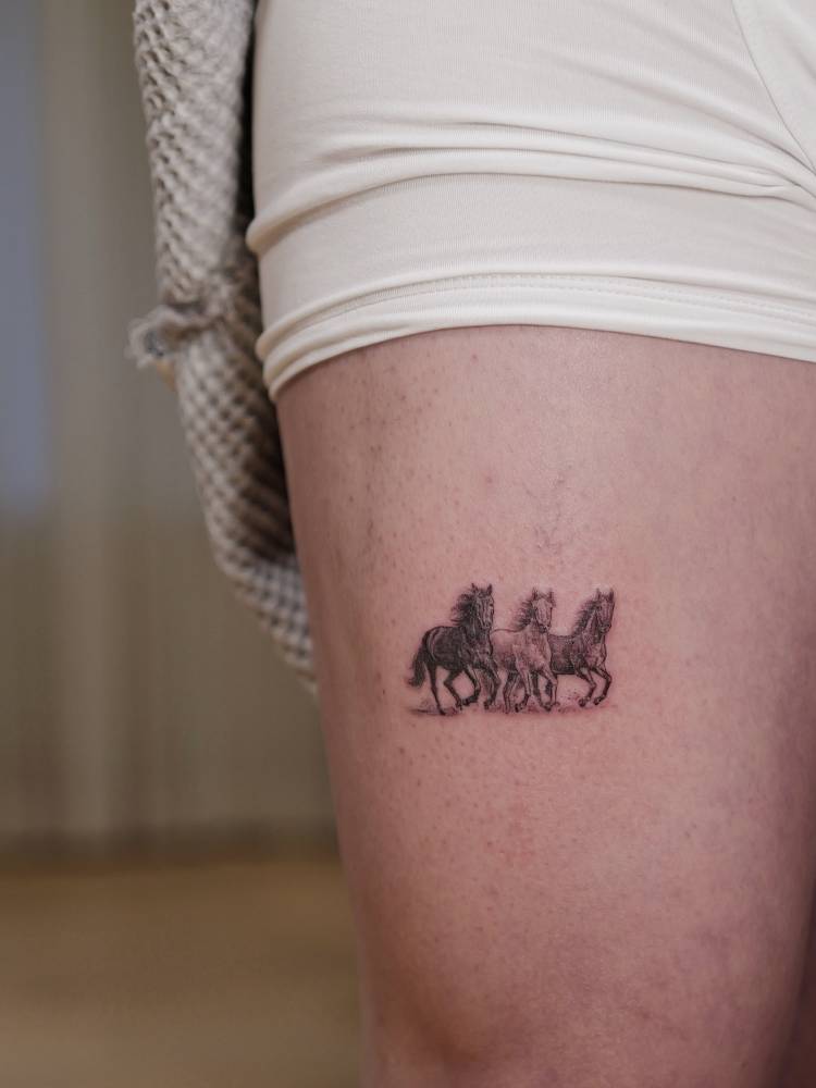 Wild horses tattoo located on the thigh, micro-realistic style.