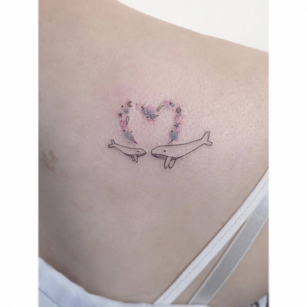 Whales and galaxy heart tattoo located on the shoulder blade.