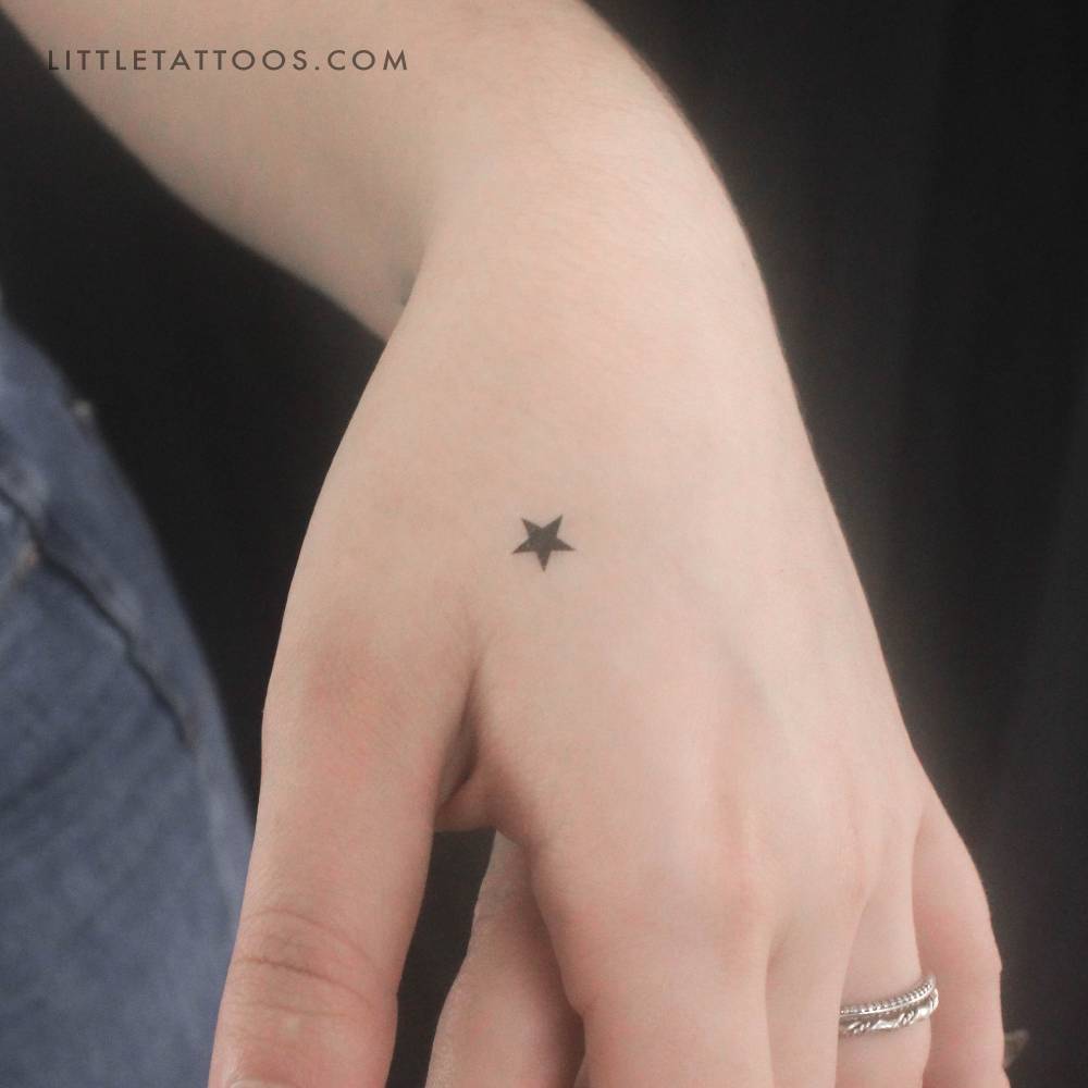Tiny minimalistic black star temporary tattoo located on the hand.