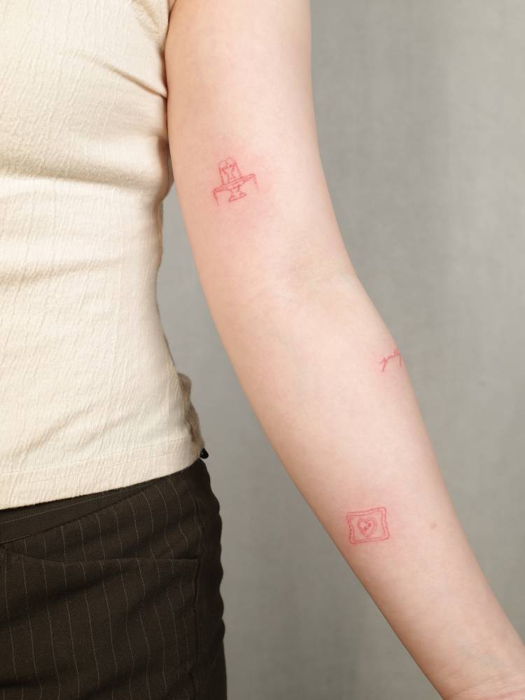 Water fountain and red heart tattoos located on the arm.