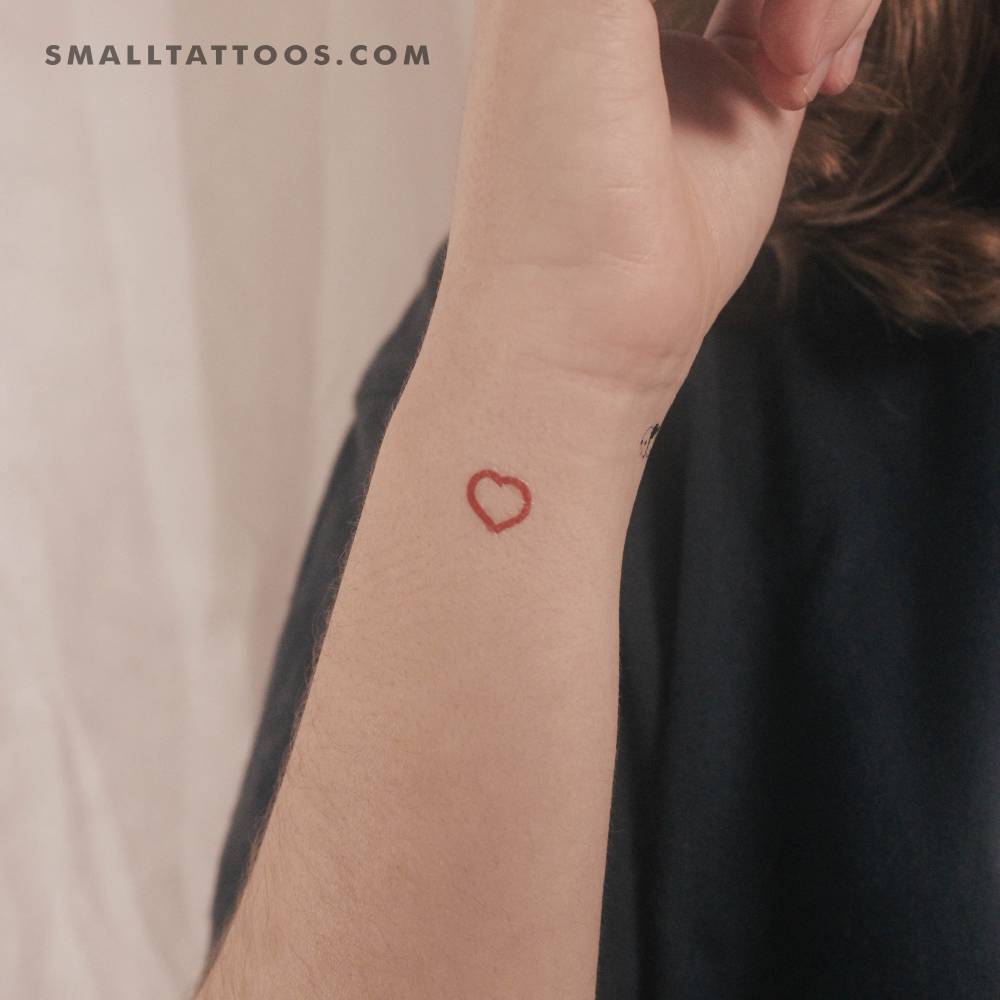 Tiny red heart outline temporary tattoo located on the wrist.