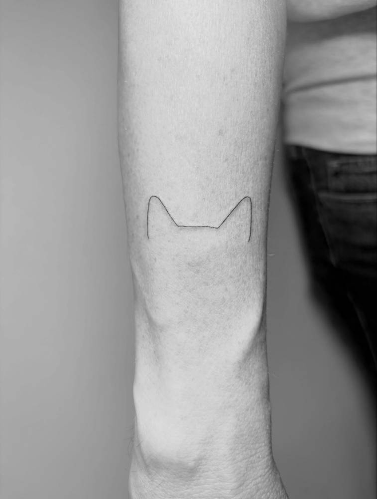 Minimalist dog ears tattoo located on the wrist.