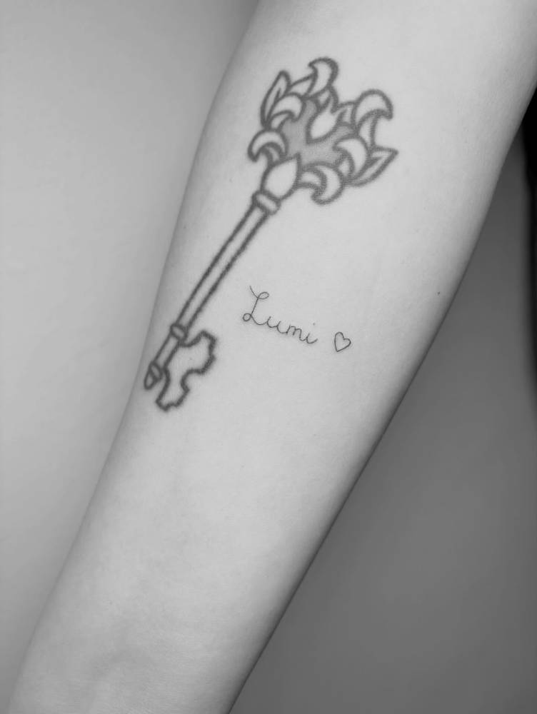Name "Lumi" and tiny heart tattoo located on the inner forearm.