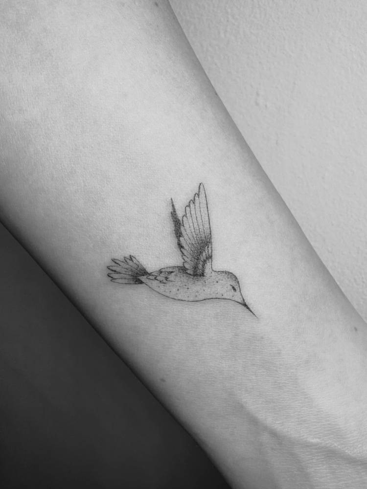 Hummingbird in illustrative style tattooed on the wrist.