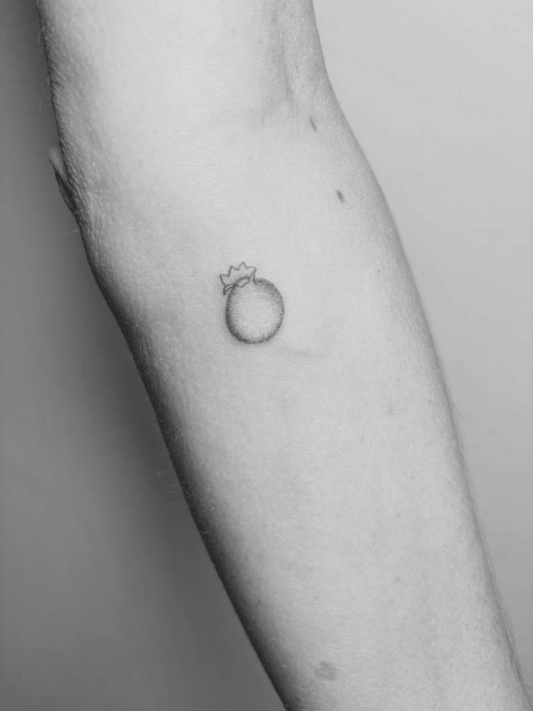 Tiny blueberry tattoo located on the inner forearm, illustrative style.