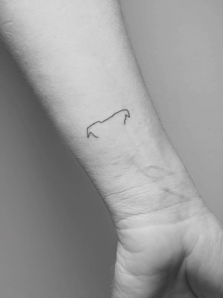 Tiny dog ears tattoo in minimalist style placed on the wrist.
