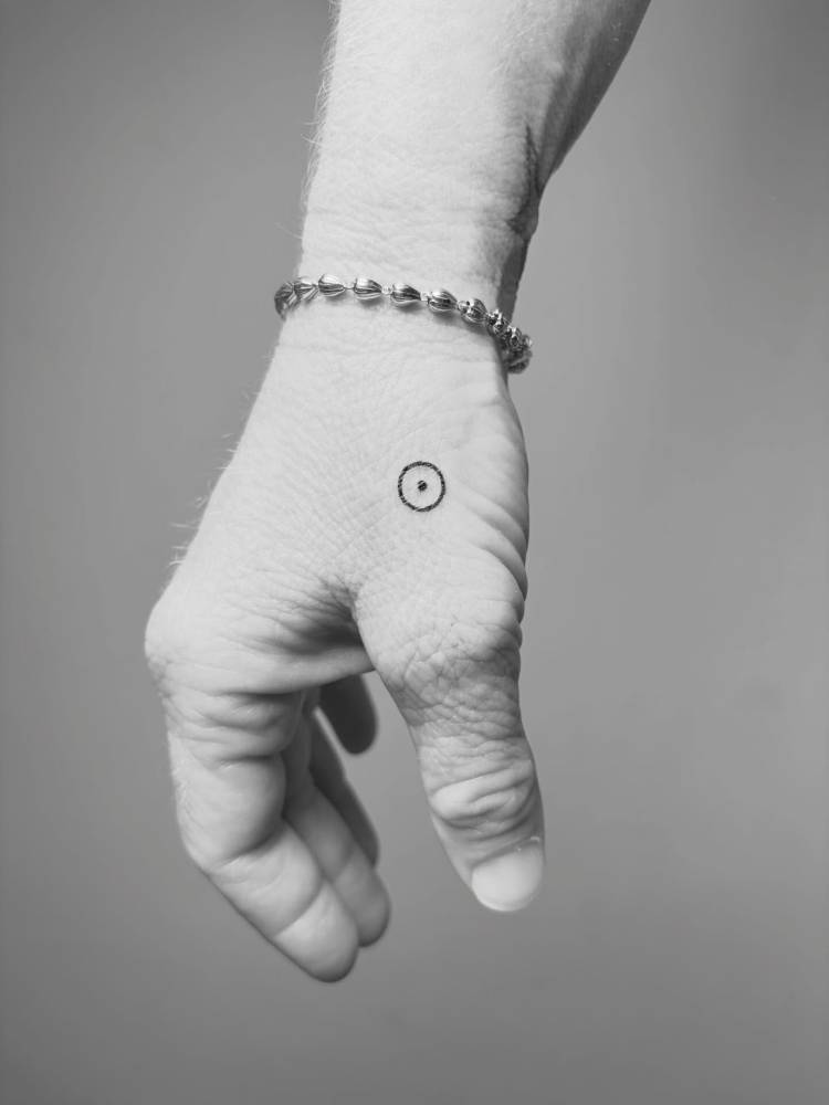 Solar planet symbol tattooed on the hand, minimalist style.
