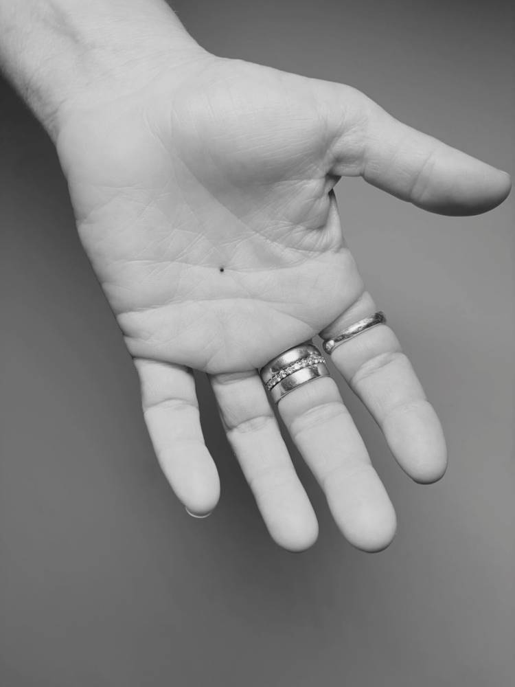 Tiny minimalist dot tattoo located on the palm.