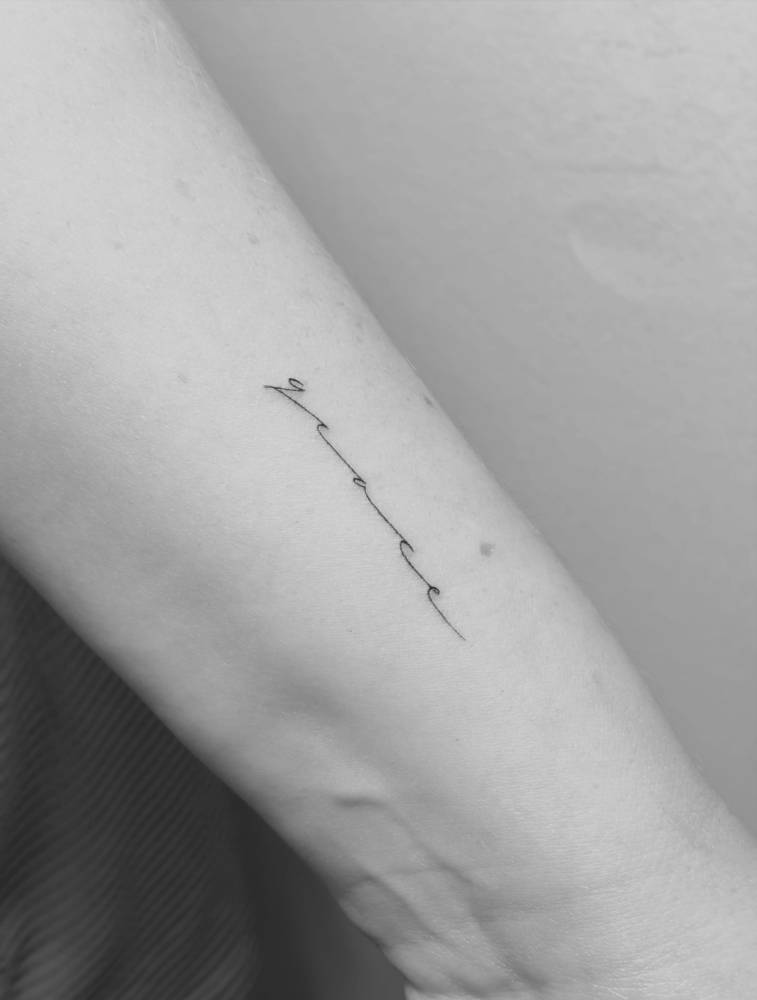 Handwritten font word "grace" tattooed on the wrist.