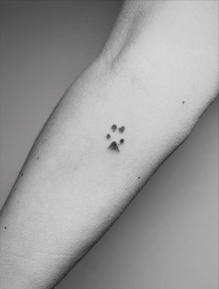 Dog paw print tattoo located on the inner forearm.