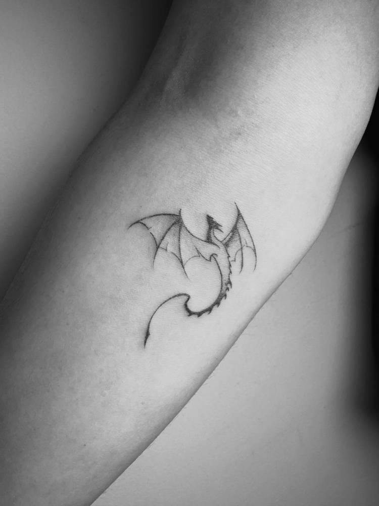Illustrative style dragon tattoo located on the inner forearm.