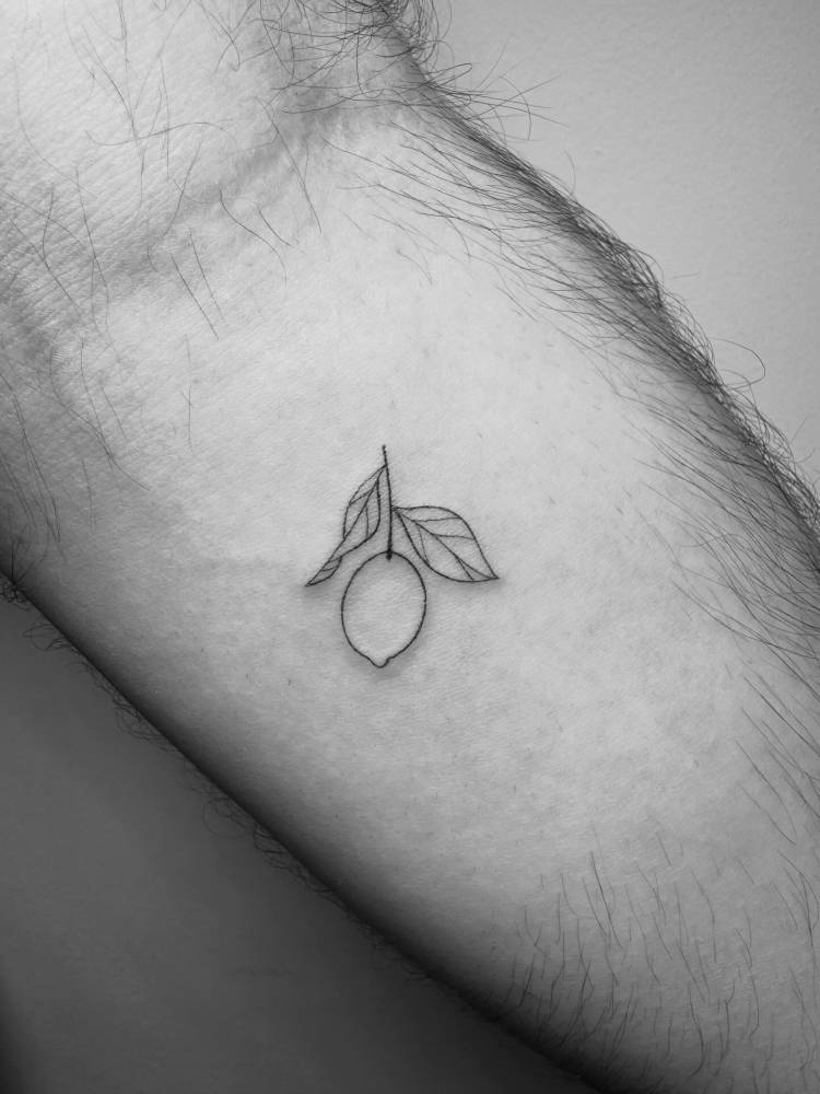 Lemon tattoo in fine line style located on the inner forearm.
