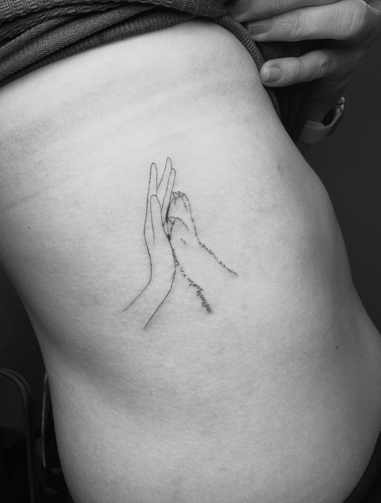 Dog high five tattoo located on the rib, fine line style.