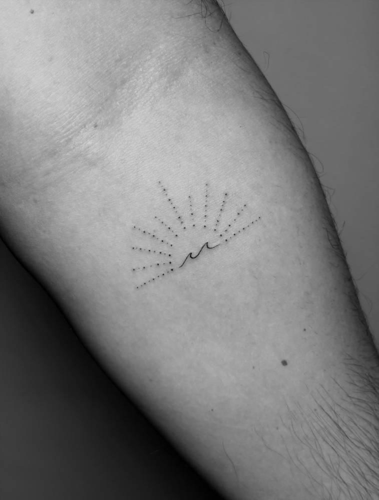 Single needle sun and wave tattoo located on the inner forearm.