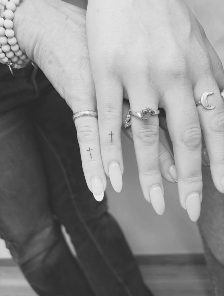 Tiny minimalist matching cross tattoo for mother and daughter.