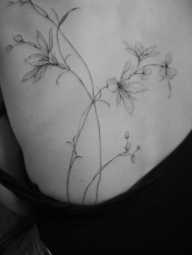 Wildflowers back tattoo in illustrative style.