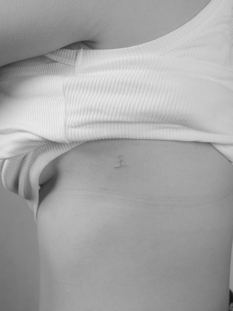 Little letter "E" tattoo located on the rib.